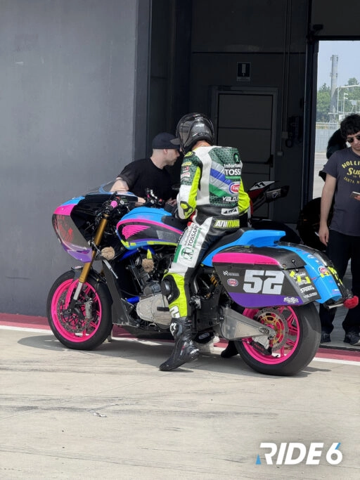 A rider prepares to test a colorful motorcycle at a track, showcasing Ride 6