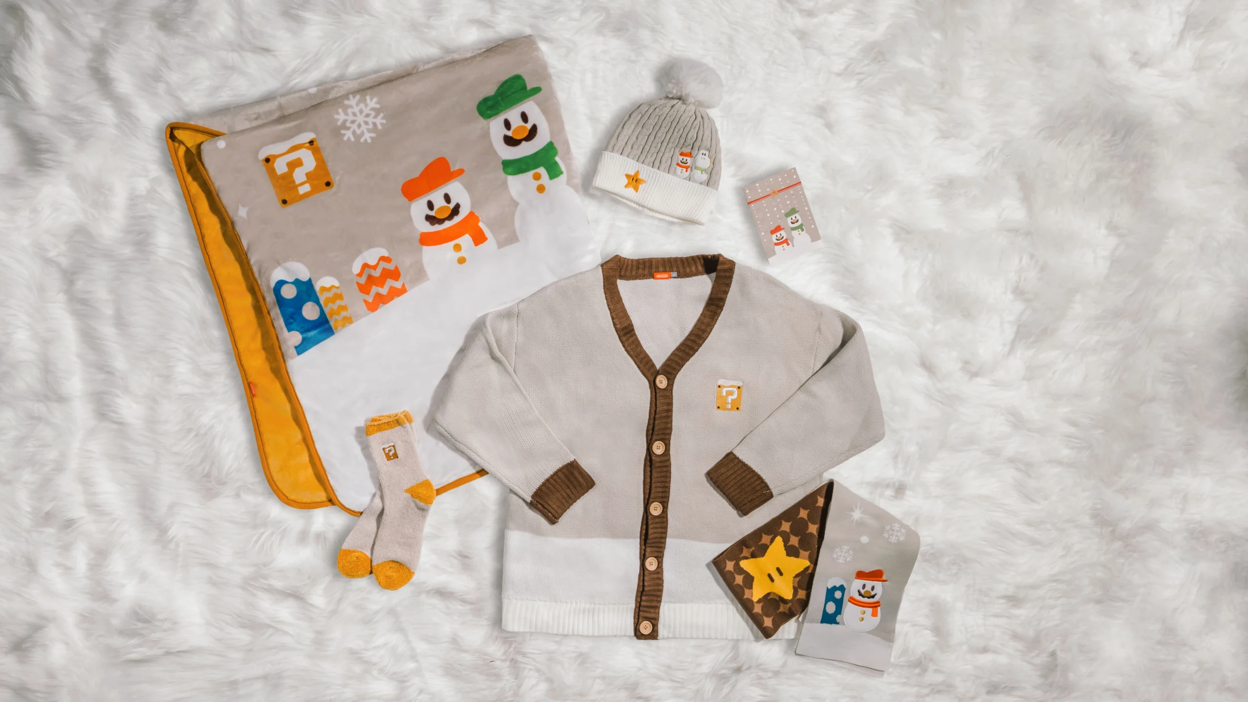 Holiday merchandise featuring cozy Nintendo-themed apparel and accessories on a fluffy white background.