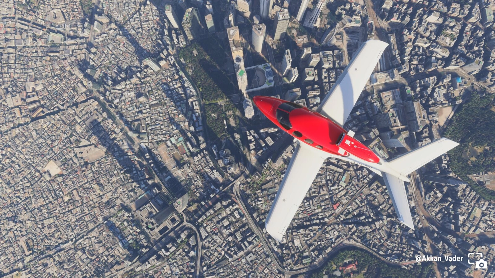 Birdseye view of a red plane soaring above a sprawling cityscape in Microsoft Flight Simulator. #PSshare #PSBlog