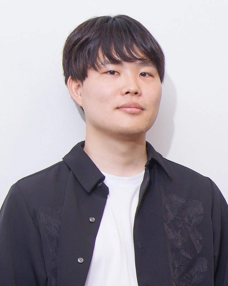 Man in a black shirt with a neutral expression against a plain white background