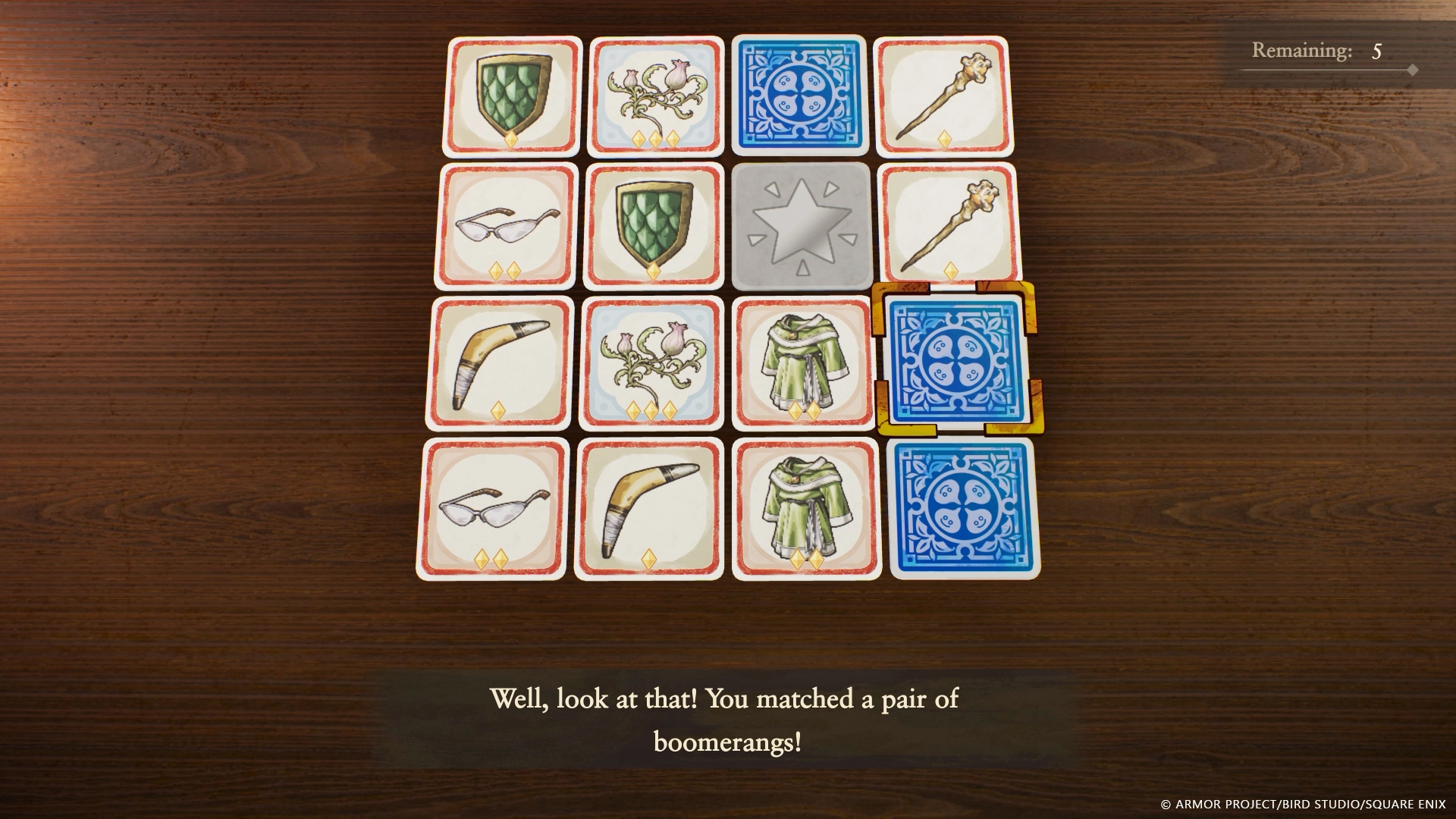 A memory card game screen showing matched pairs of boomerangs, shields, and other items on a wooden table