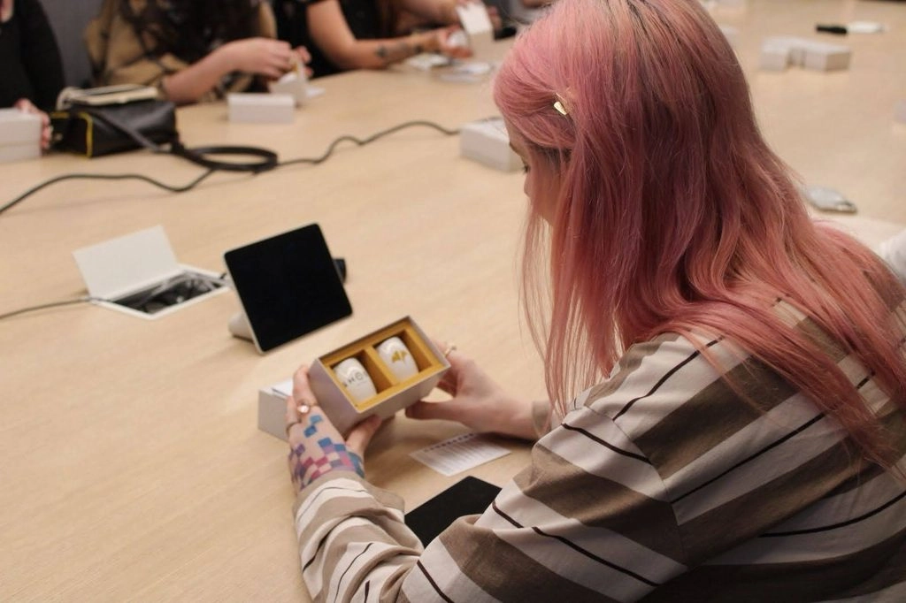 Person with pink hair examines collectible figures at a table, highlighting creative storytelling