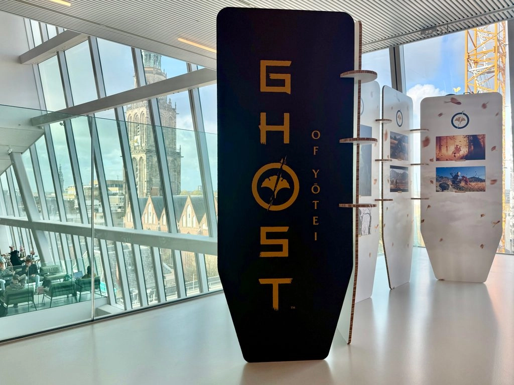 Display stand featuring Ghost of Yōtei branding in a modern, glass-walled exhibition space