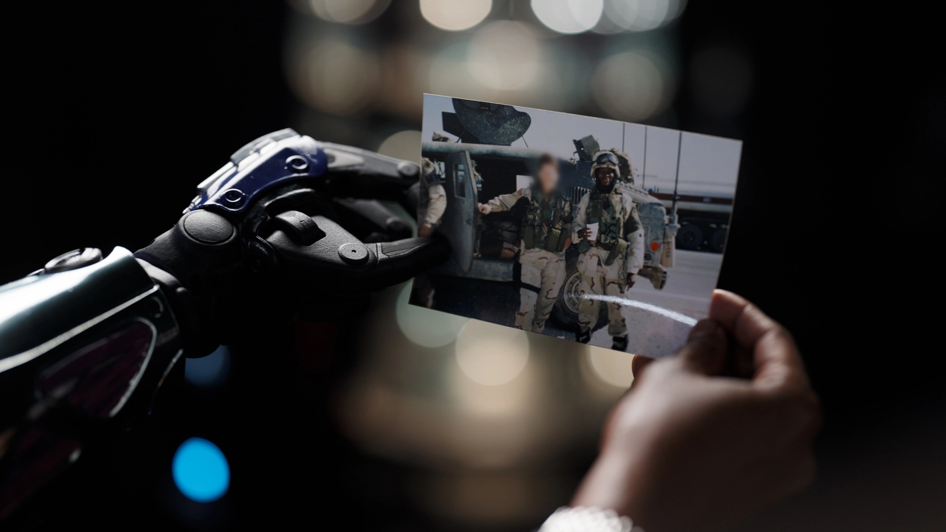 A veteran with a robotic arm holds a photo of soldiers, symbolizing honor and support for veterans