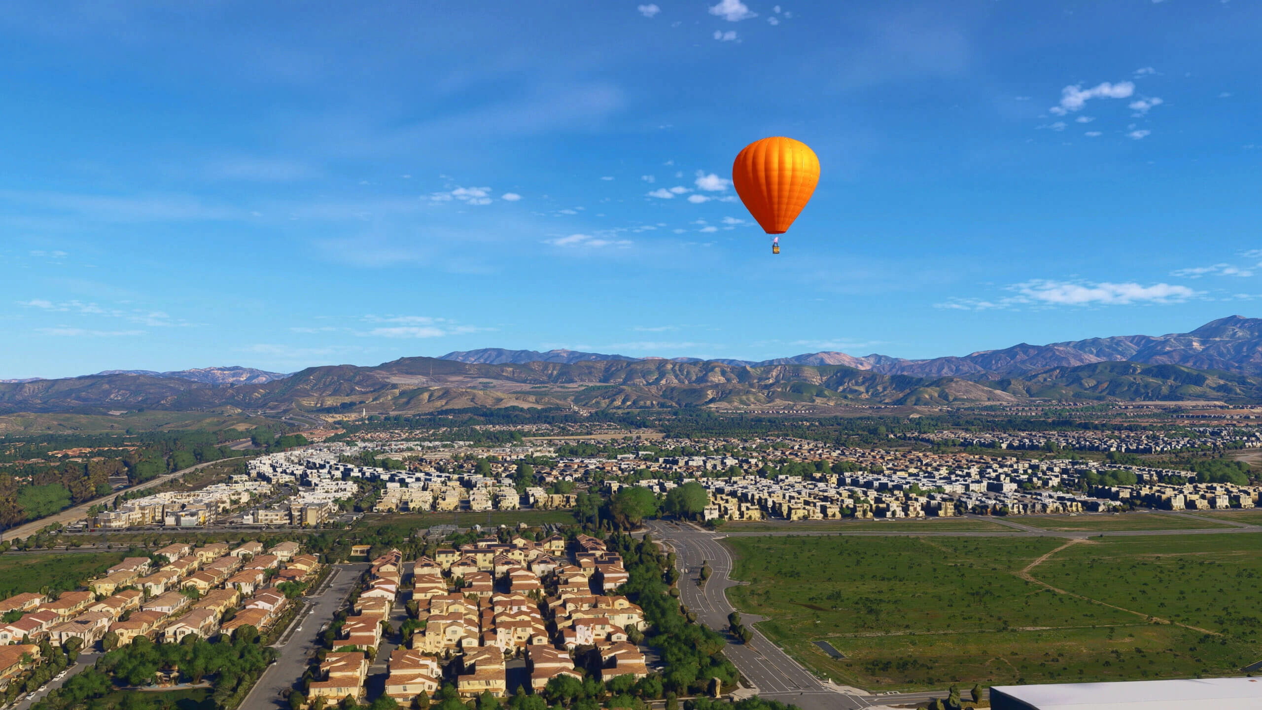 Hot air balloon soaring over a detailed California cityscape with mountains in the background