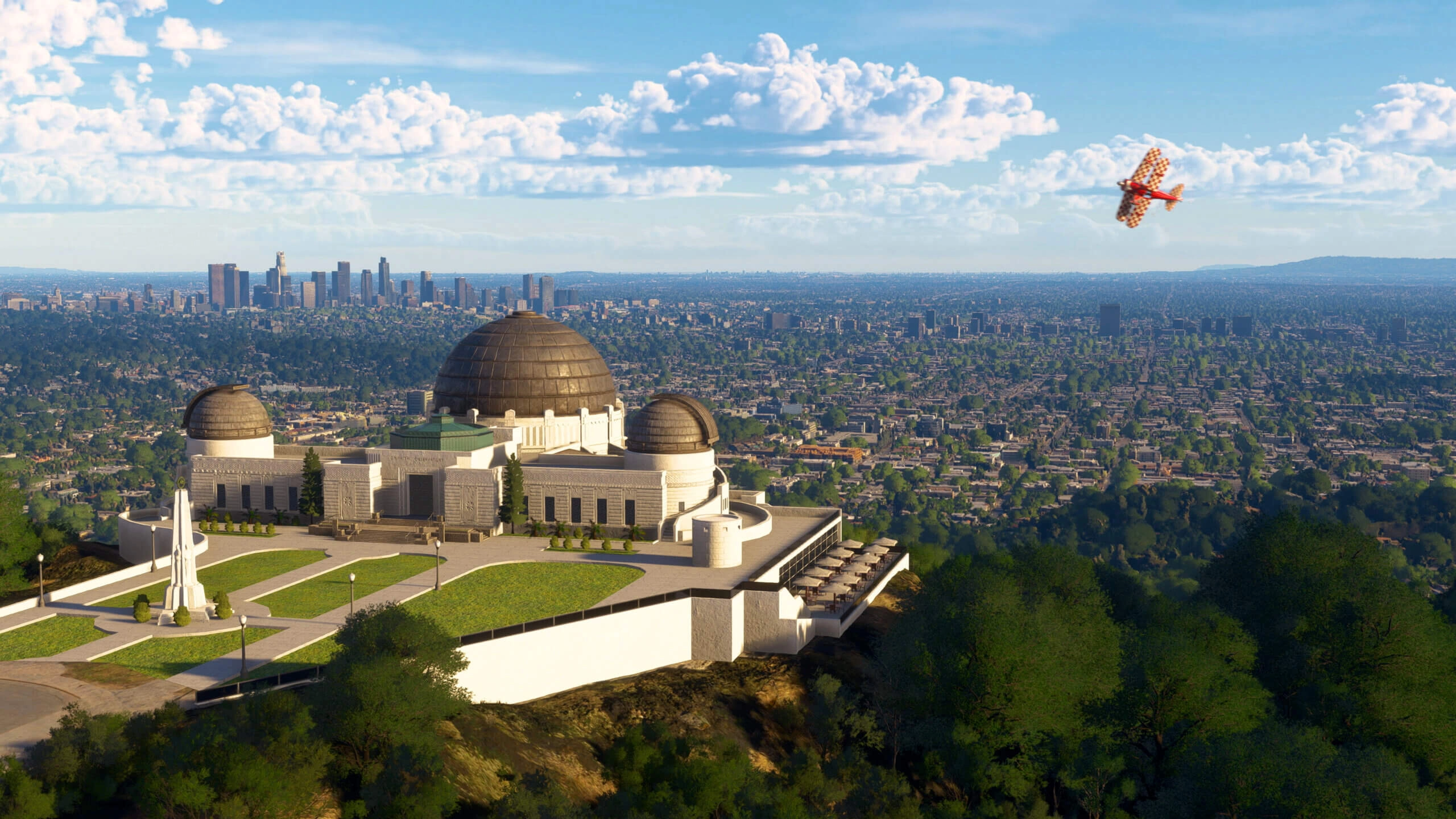 Griffith Observatory overlooking Los Angeles skyline with a small plane flying in a clear blue sky