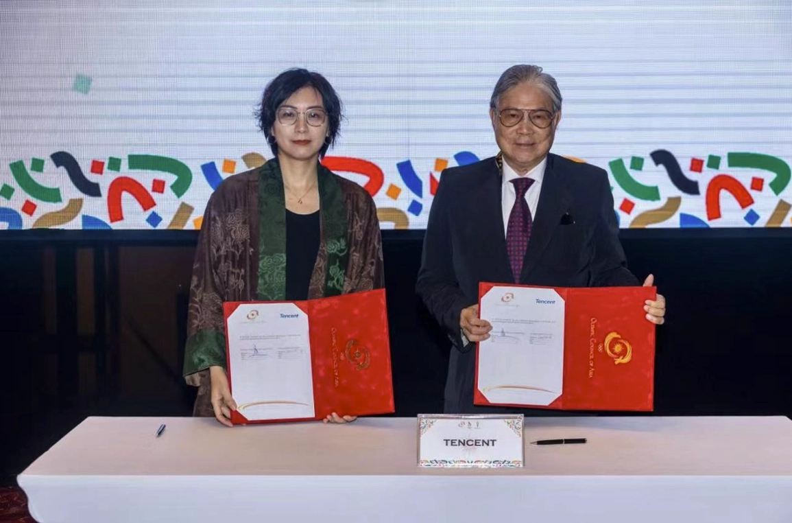 Tencent Esports and OCA representatives holding signed agreements at a partnership announcement event