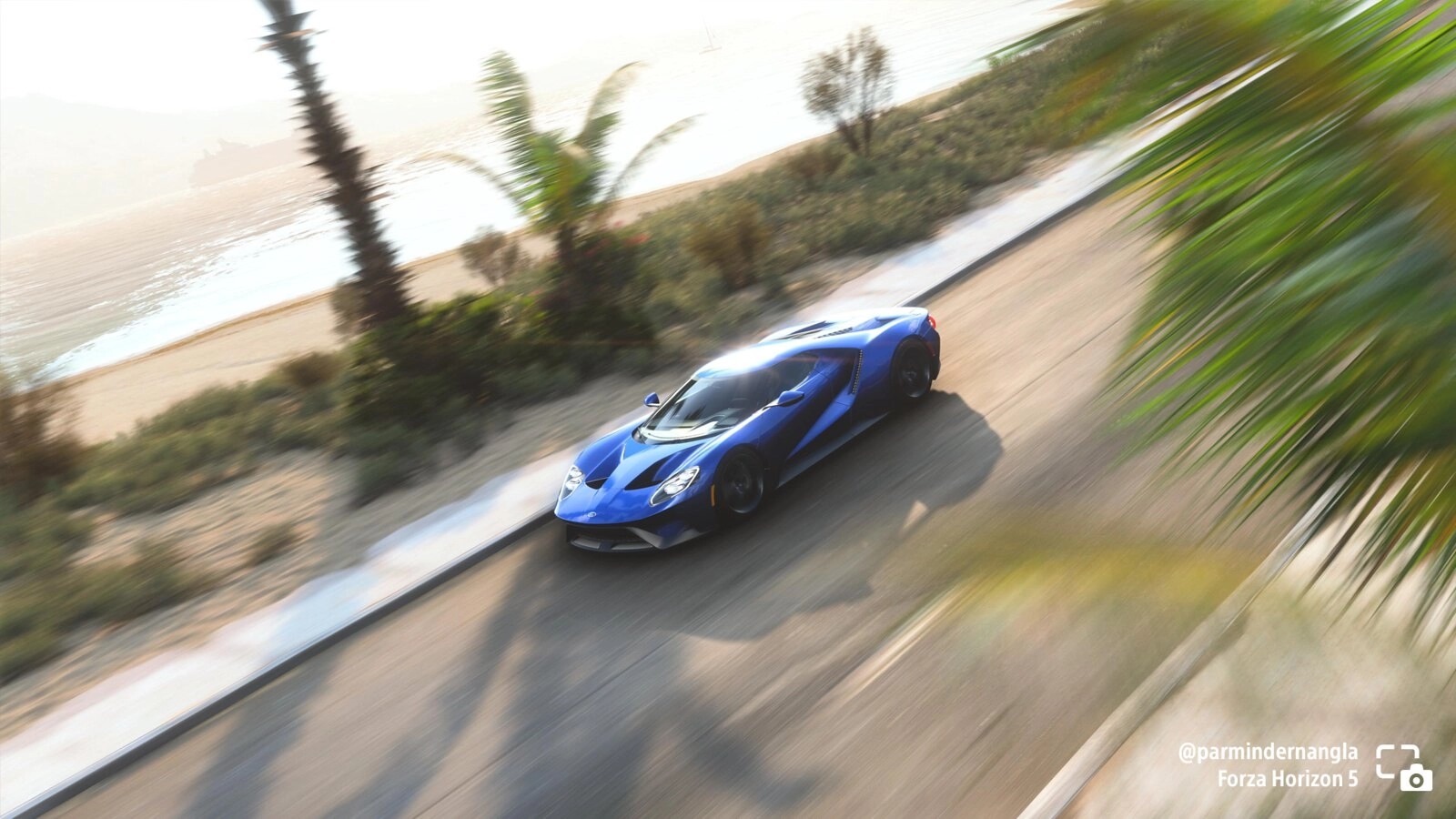 Blue Ford GT speeding along a coastal road in Forza Horizon 5, surrounded by palm trees and ocean views