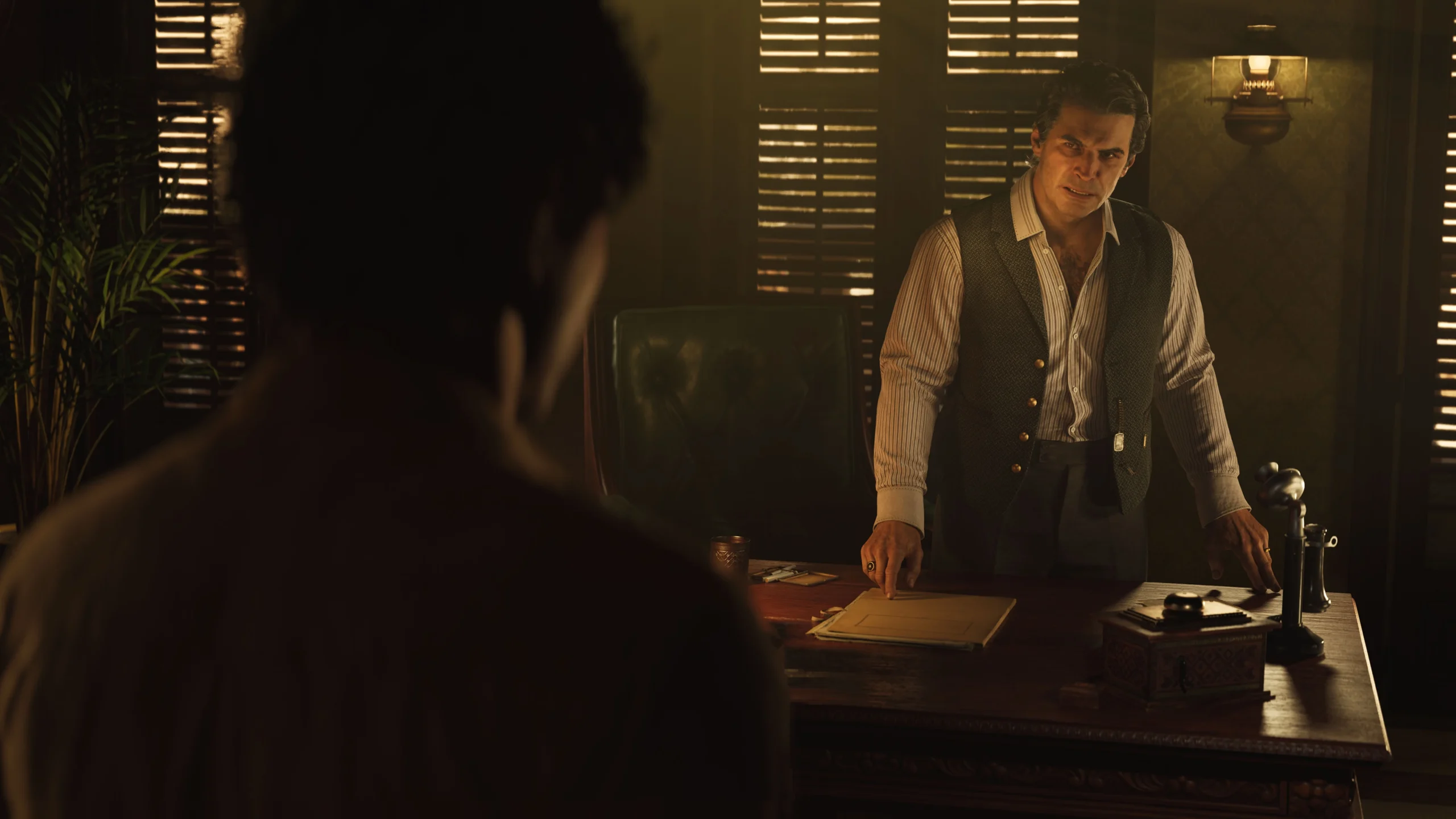 A man in a dimly lit office stands behind a desk, engaging in a tense conversation with another person