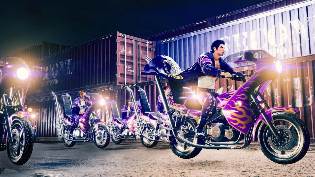 Motorcycles with vibrant purple and yellow designs parked near shipping containers at night, riders in action