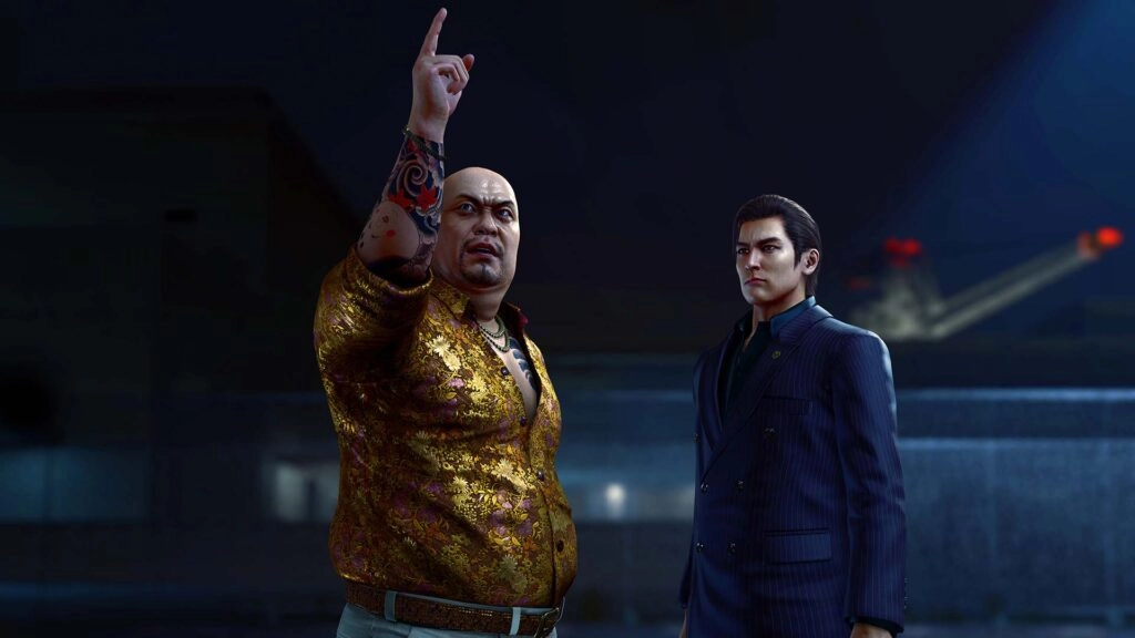 Two men stand in a dimly lit urban setting, one pointing upwards, both appearing serious and focused