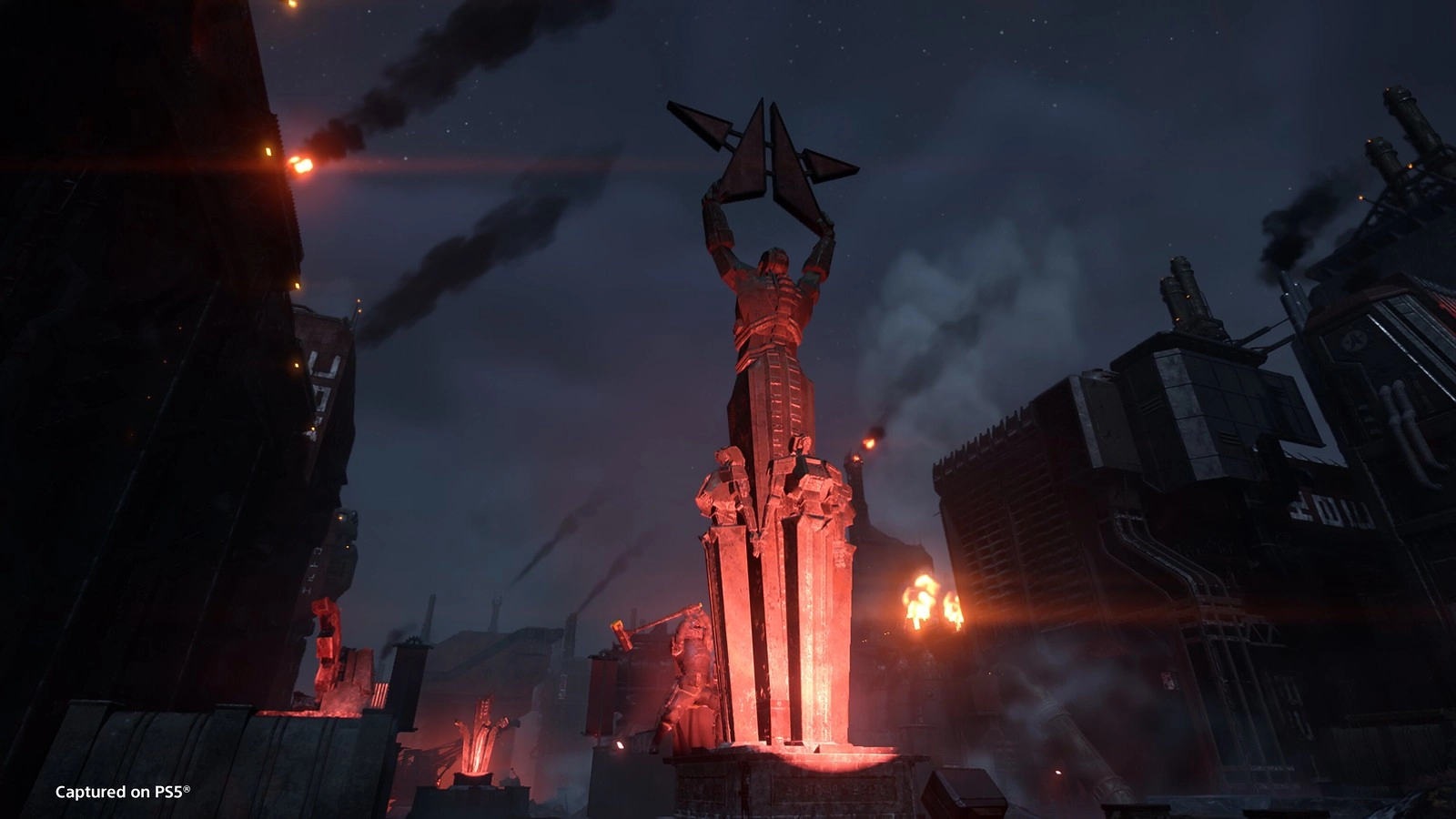 A towering statue in a dark, industrial cityscape with smoke and glowing red lights in Cyberstan