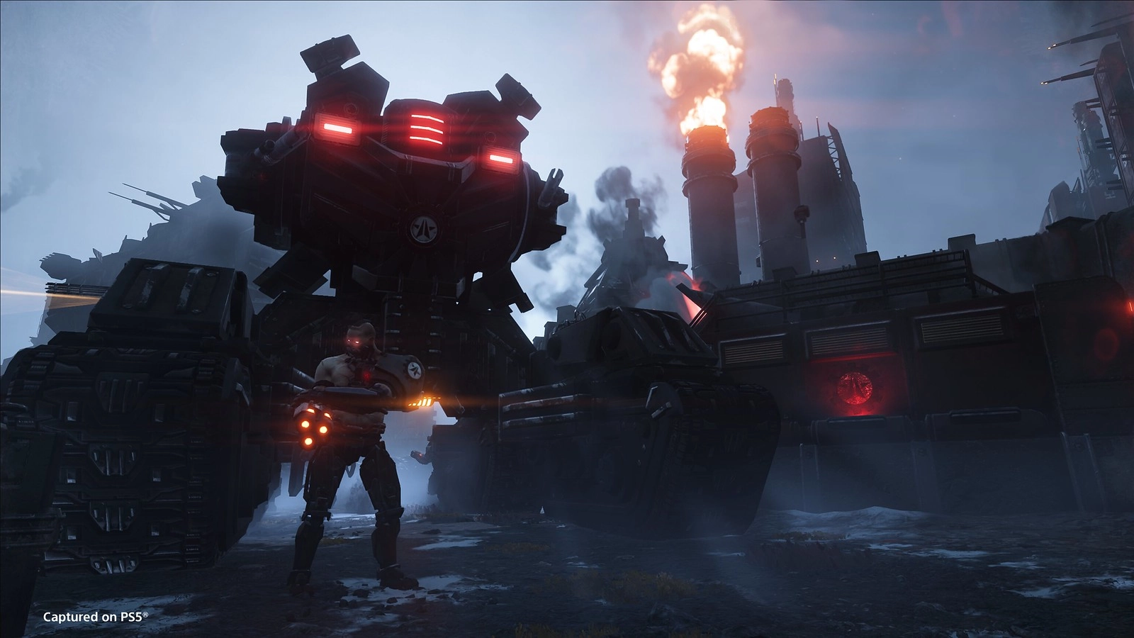 A Helldiver stands ready in front of a massive war machine in Cyberstan's industrial landscape
