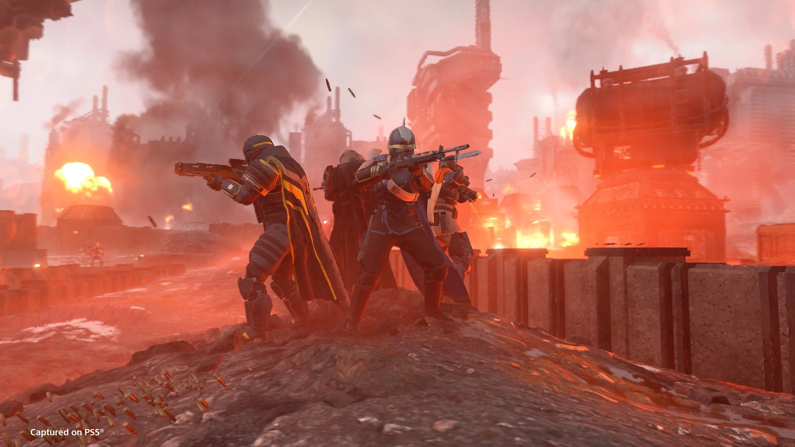 Helldivers in combat gear stand ready amidst fiery, industrial ruins of Cyberstan's factory cities