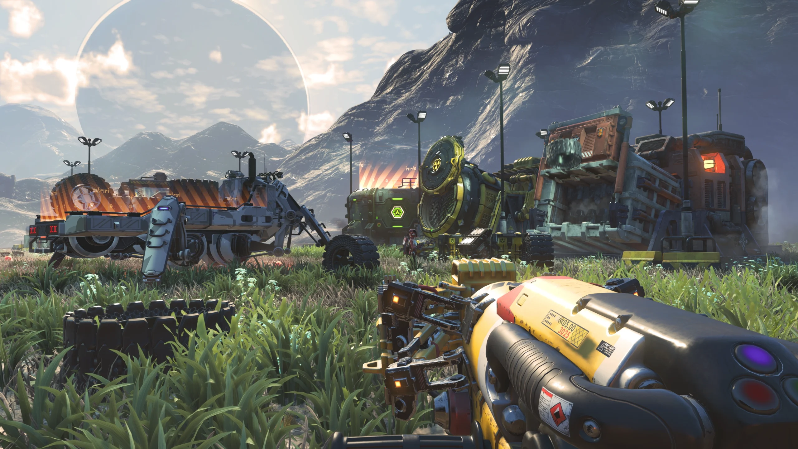 Player holding a gravity gun in No Man's Sky, facing futuristic trucks and machinery on an alien landscape