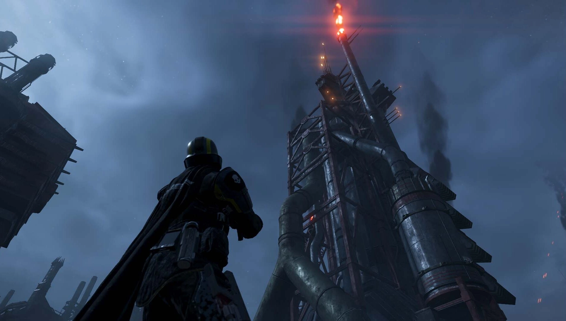 A Helldiver stands ready beneath a towering industrial structure on the icy planet of Cyberstan at night