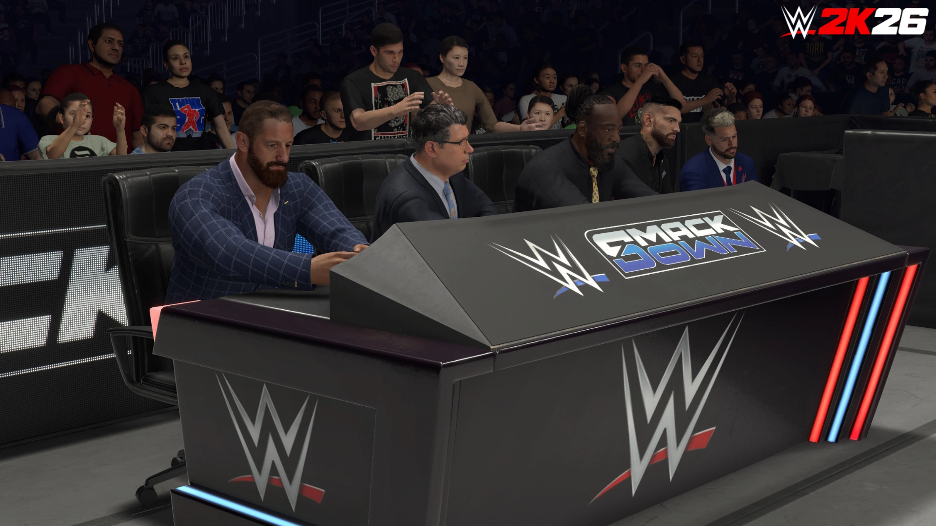 WWE 2K26 commentary team at the SmackDown announcer table, showcasing new presentation features